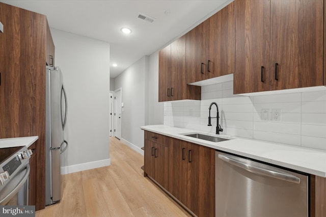 kitchen featuring decorative backsplash, light wood-type flooring, sink, and appliances with stainless steel finishes