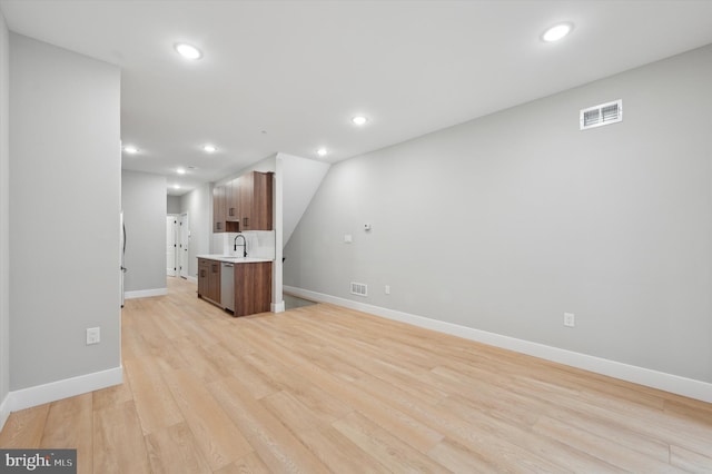 unfurnished living room featuring sink and light hardwood / wood-style flooring