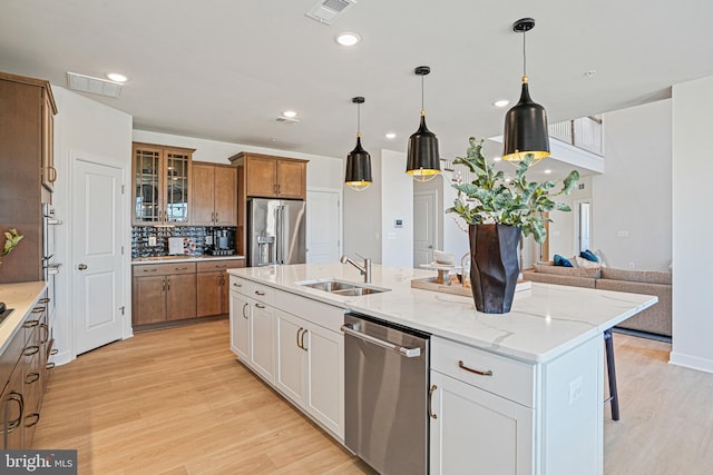 kitchen with white cabinetry, sink, stainless steel appliances, and a center island with sink