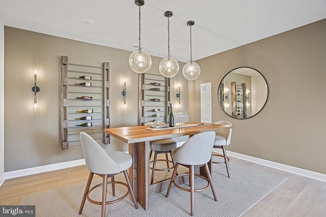 dining area with bar and light hardwood / wood-style flooring