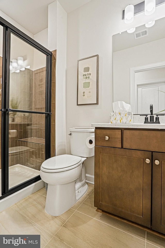 bathroom featuring vanity, a shower with door, and toilet