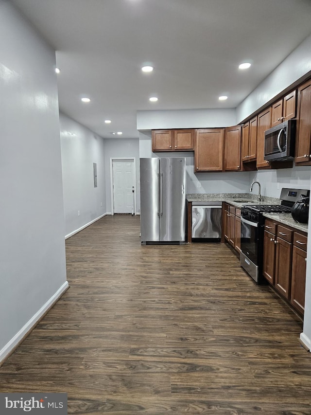 kitchen featuring dark wood-type flooring, stainless steel appliances, sink, and light stone counters