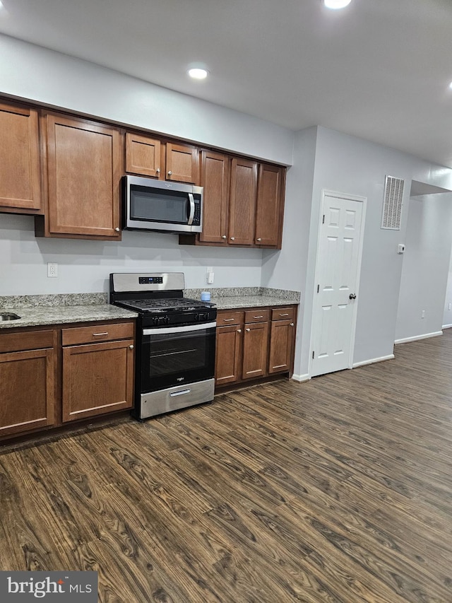 kitchen with light stone counters, stainless steel appliances, and dark hardwood / wood-style flooring