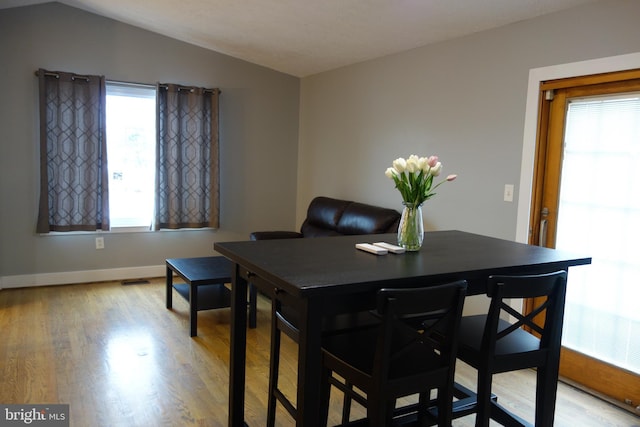 dining area featuring vaulted ceiling and light wood-type flooring