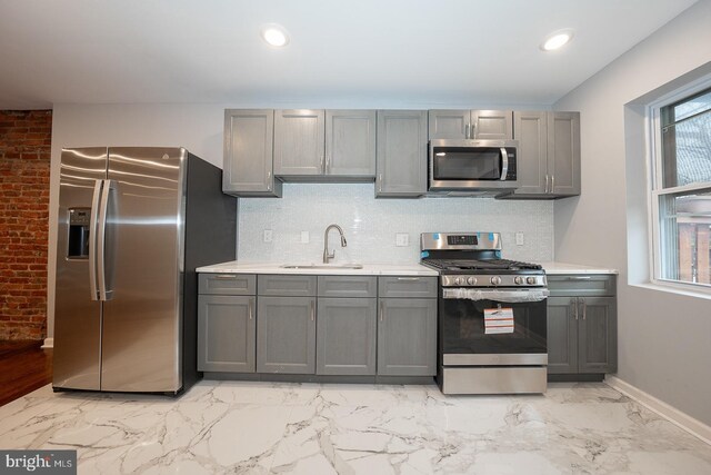 kitchen featuring gray cabinets, sink, stainless steel appliances, and tasteful backsplash