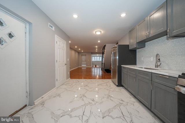 kitchen featuring backsplash, gray cabinets, sink, and appliances with stainless steel finishes