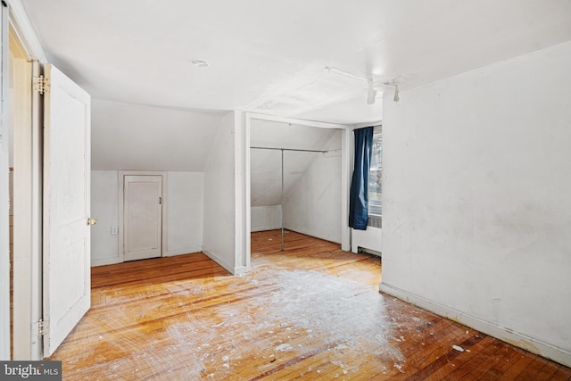 additional living space with light hardwood / wood-style floors, radiator, and vaulted ceiling