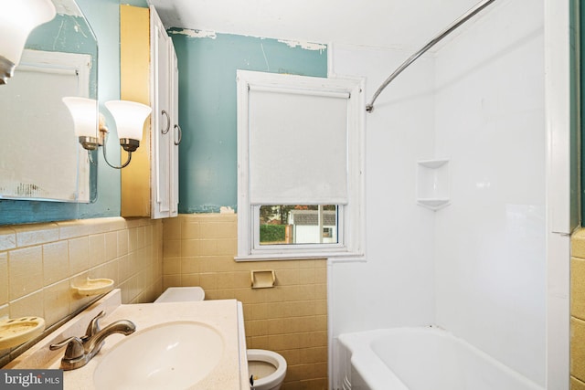 full bathroom featuring vanity, toilet, tile walls, and tub / shower combination