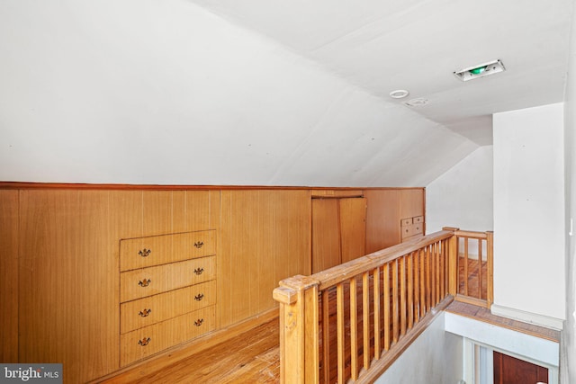 interior space with light hardwood / wood-style flooring, vaulted ceiling, and wood walls