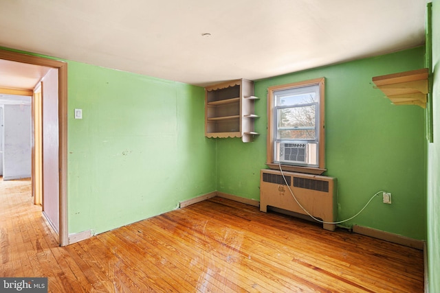 spare room featuring cooling unit, light wood-type flooring, and radiator heating unit