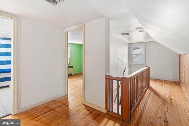 hall with radiator heating unit, lofted ceiling, and light wood-type flooring