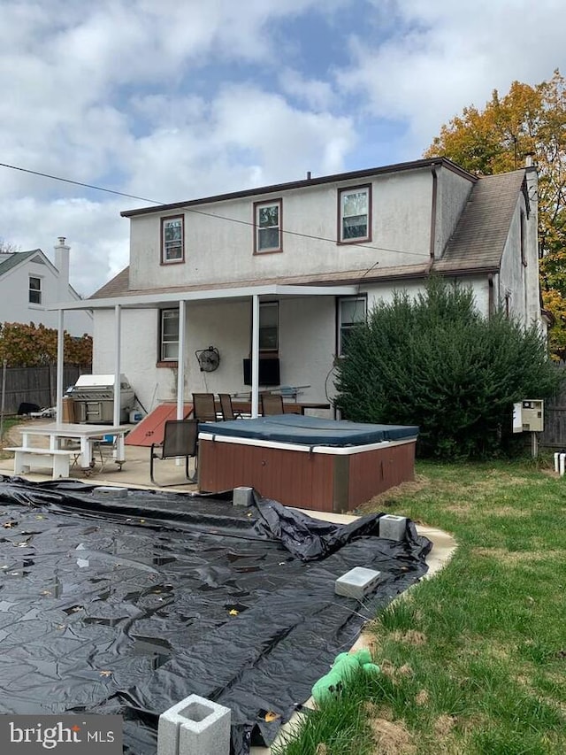 back of house featuring a patio, a yard, and a hot tub