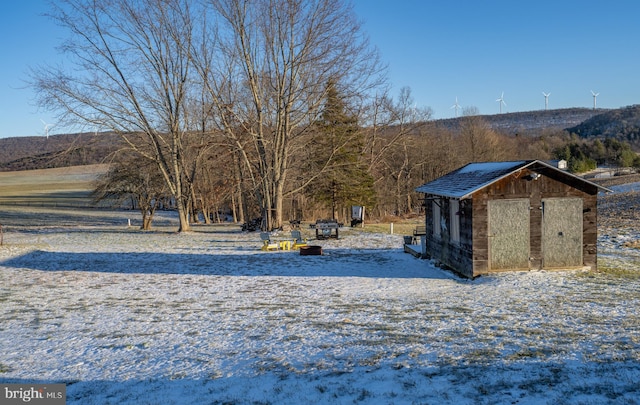 yard layered in snow with a mountain view and a shed