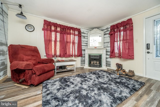 living room featuring hardwood / wood-style floors, ornamental molding, and wooden walls