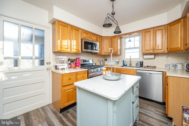 kitchen with a center island, dark wood-type flooring, sink, hanging light fixtures, and stainless steel appliances