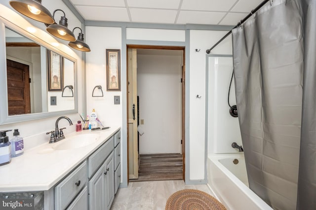 bathroom featuring a drop ceiling, wood-type flooring, shower / bath combo with shower curtain, and vanity