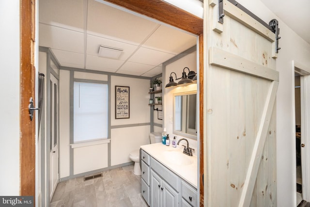 bathroom featuring a paneled ceiling, vanity, wood-type flooring, and toilet