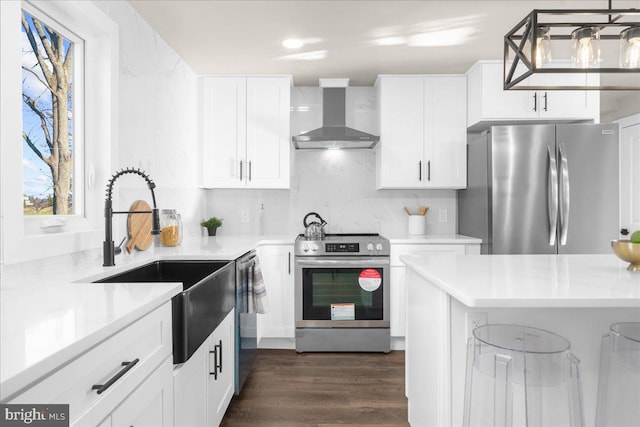 kitchen with backsplash, wall chimney exhaust hood, stainless steel appliances, sink, and white cabinetry