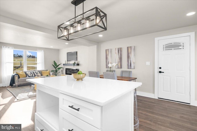 kitchen featuring dark hardwood / wood-style flooring, white cabinetry, a center island, and decorative light fixtures