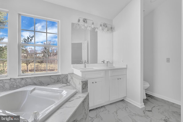 bathroom featuring vanity, a relaxing tiled tub, and toilet