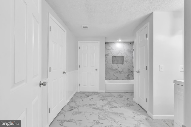 bathroom with vanity, a textured ceiling, and tiled shower / bath