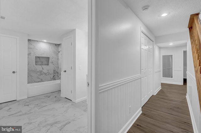 hall featuring hardwood / wood-style floors and a textured ceiling