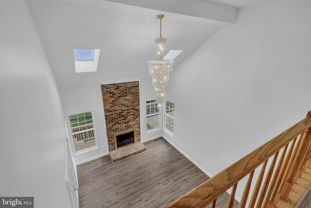 living room featuring lofted ceiling with skylight, hardwood / wood-style floors, plenty of natural light, and a brick fireplace