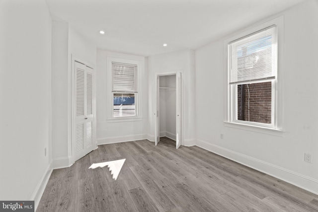 unfurnished bedroom featuring two closets and light wood-type flooring