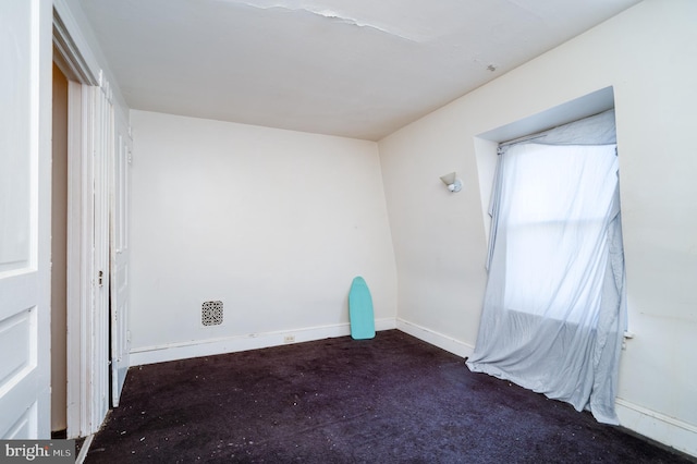 unfurnished room with dark colored carpet