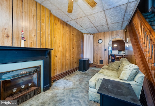 living room with wooden walls, a drop ceiling, and carpet floors