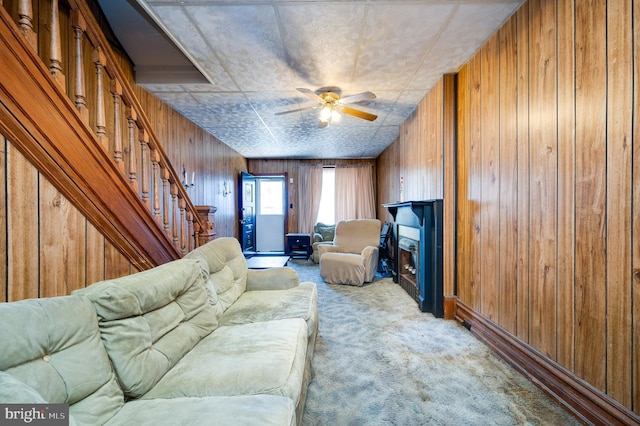 carpeted living room featuring wood walls and ceiling fan