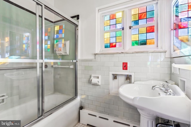 bathroom featuring baseboard heating, shower / bath combination with glass door, plenty of natural light, and sink