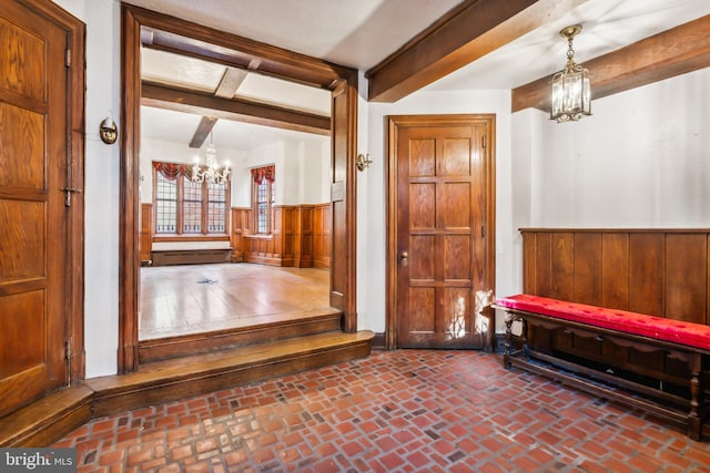 foyer with beamed ceiling, wooden walls, and a chandelier