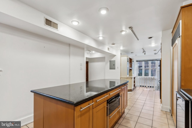 kitchen with electric panel, a center island, light tile patterned floors, and dark stone countertops