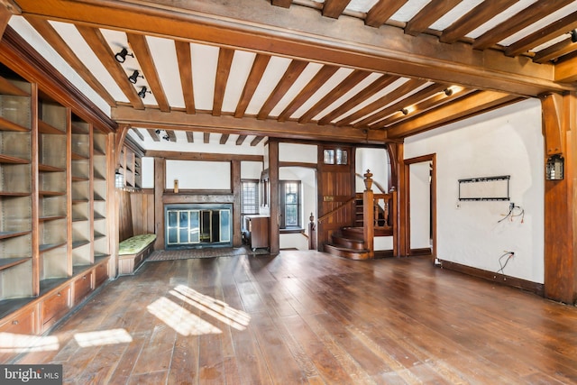 unfurnished living room with beam ceiling and dark hardwood / wood-style flooring