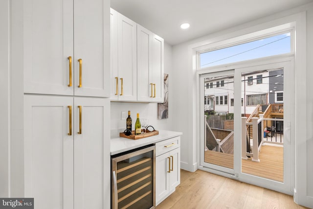 bar featuring white cabinets, beverage cooler, and light hardwood / wood-style flooring