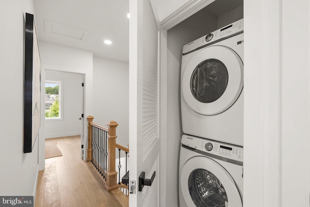 laundry area with light hardwood / wood-style floors and stacked washer and dryer