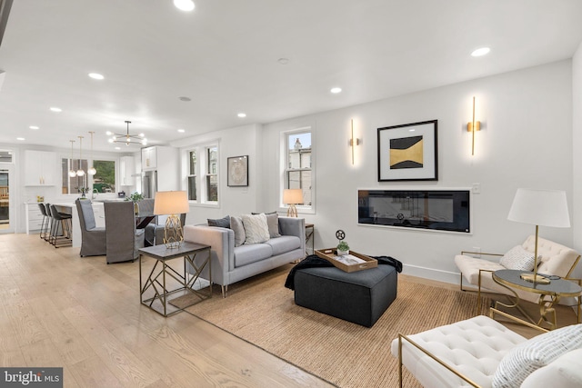 living room with plenty of natural light, a chandelier, and light hardwood / wood-style flooring