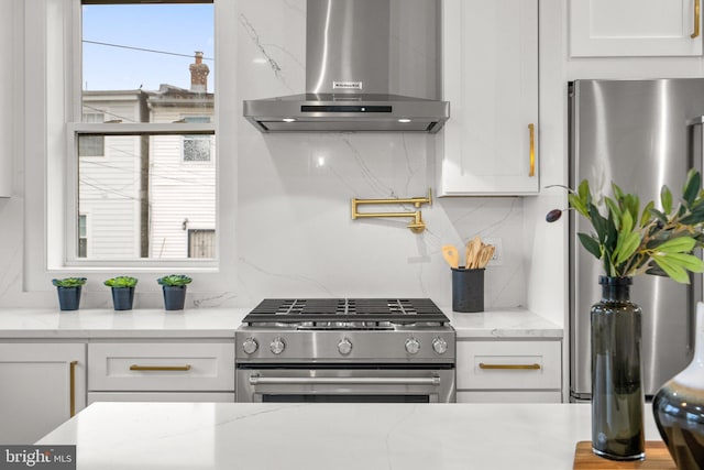 kitchen with decorative backsplash, light stone countertops, range hood, white cabinetry, and stainless steel appliances