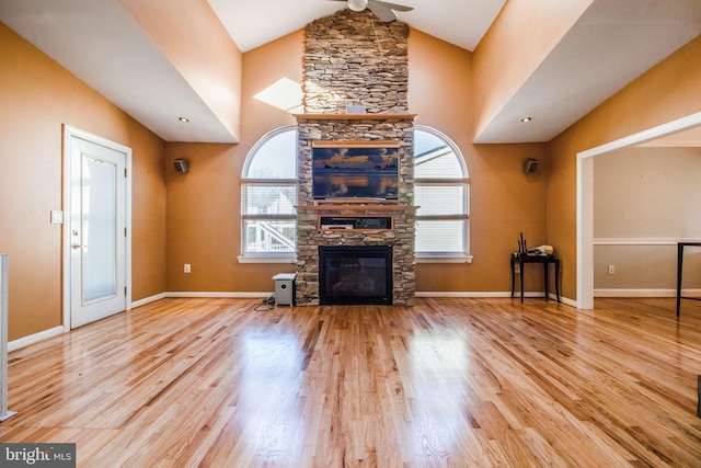 unfurnished living room featuring a fireplace, light hardwood / wood-style floors, vaulted ceiling, and plenty of natural light