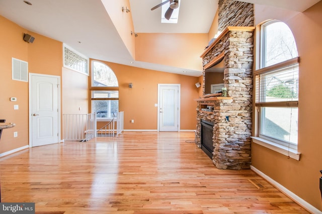 unfurnished living room featuring ceiling fan, light wood-type flooring, and a towering ceiling