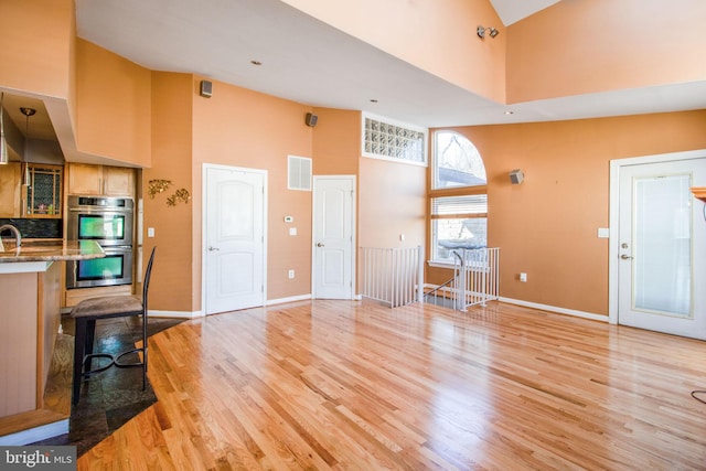 living room with light hardwood / wood-style floors, a towering ceiling, and sink