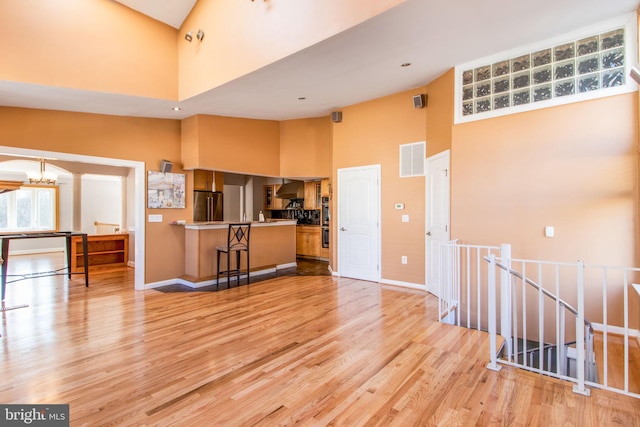 living room with light hardwood / wood-style flooring, high vaulted ceiling, and a notable chandelier