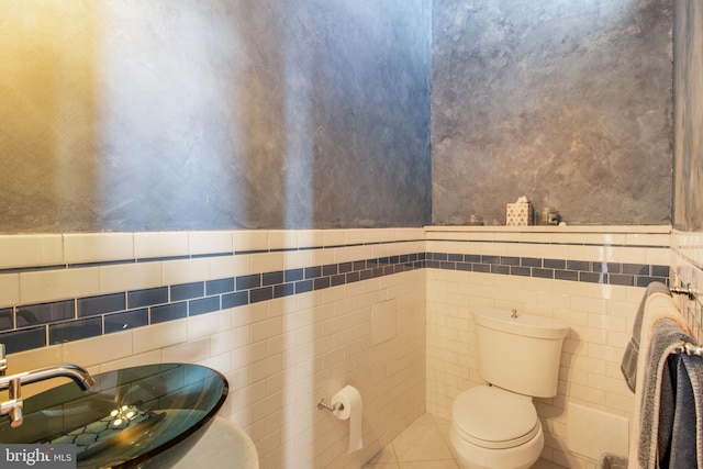 bathroom with tile patterned floors, sink, tile walls, and toilet