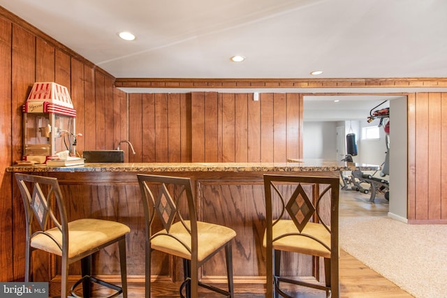 bar with wooden walls and light hardwood / wood-style flooring