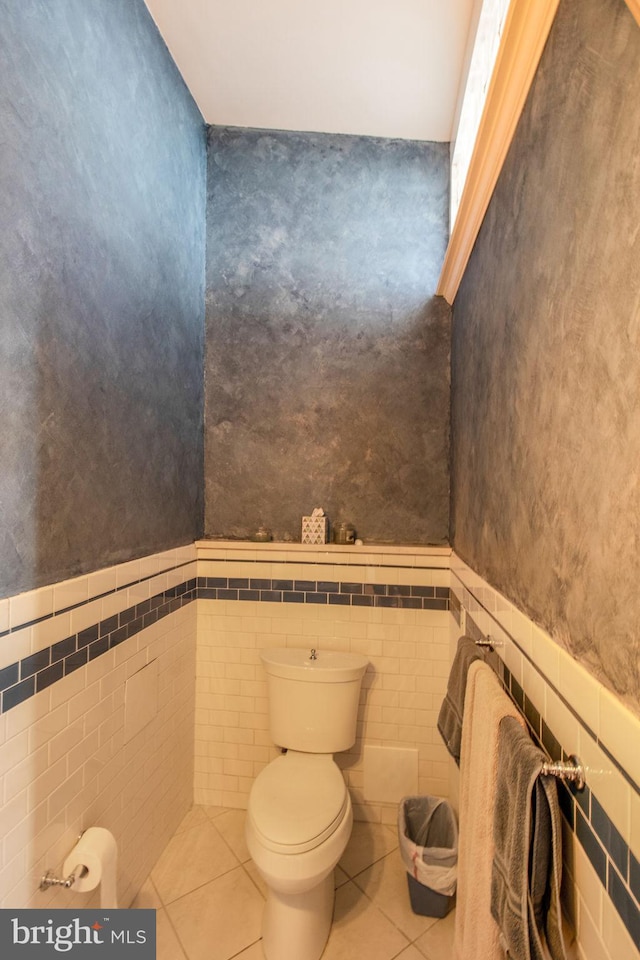 bathroom featuring toilet, tile patterned floors, and tile walls