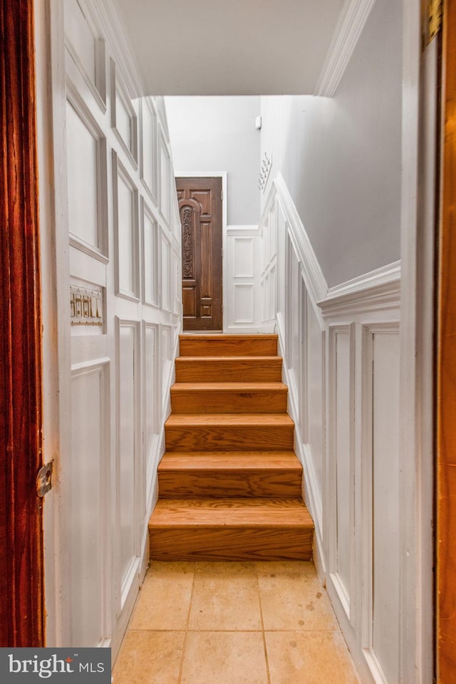 stairway featuring tile patterned floors and crown molding