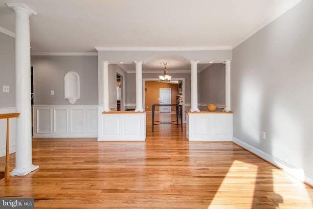 unfurnished living room with ornate columns, crown molding, a chandelier, and light hardwood / wood-style floors