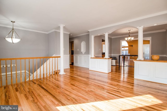 unfurnished living room featuring light hardwood / wood-style floors, crown molding, and an inviting chandelier