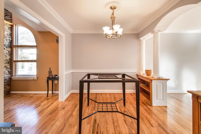 dining area with an inviting chandelier, light wood-type flooring, ornamental molding, and decorative columns